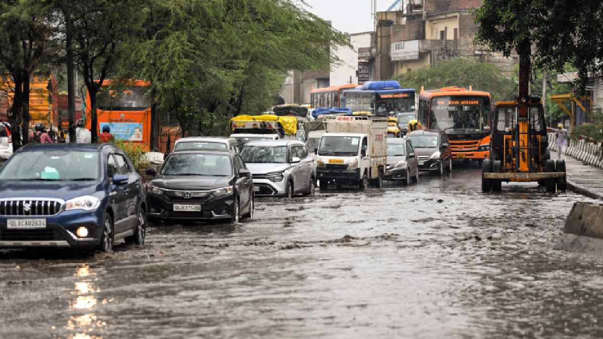 Vehciles wade through a waterlogged road after rainfall, in New Delhi. (Photo Credit: ANI)